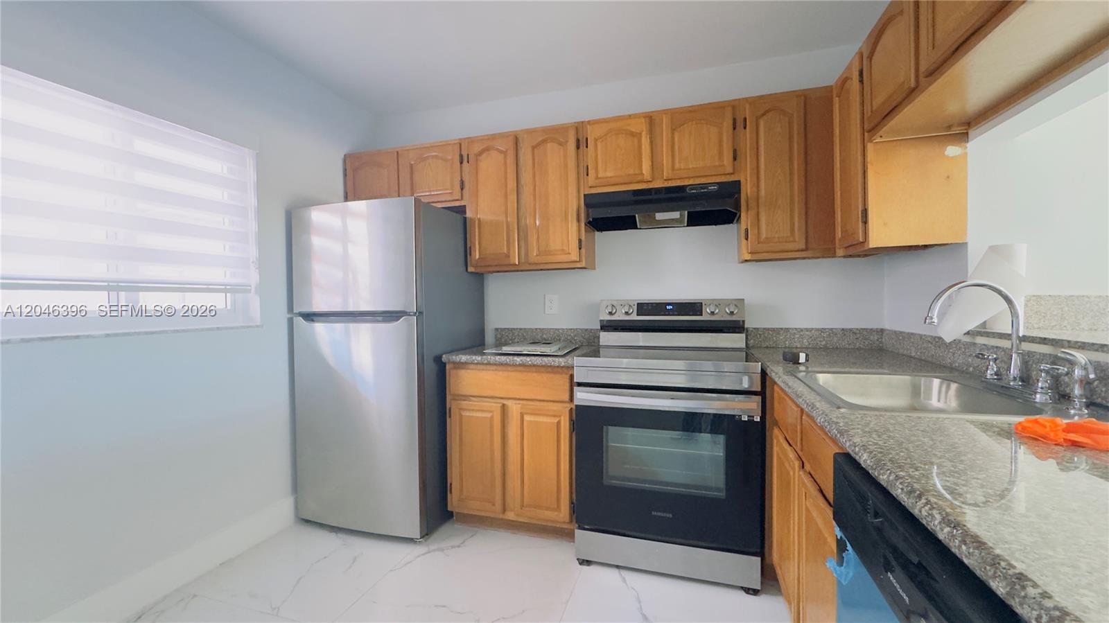 A kitchen features stainless steel appliances, wood cabinets, and granite countertops over white tile floors — 19851 SW 114th Ave # 301, Miami FL 33157, MIAMI, FL