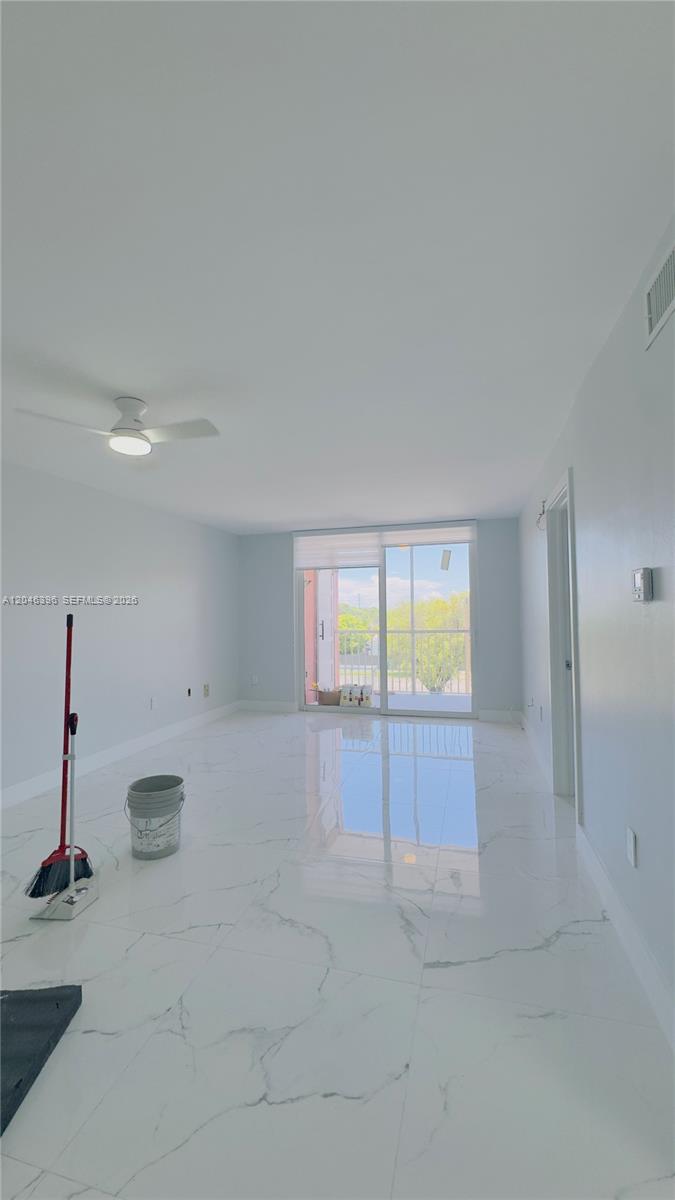 A bright, empty room features white marble-look tile flooring, a ceiling fan, and sliding glass doors — 19851 SW 114th Ave # 301, Miami FL 33157, MIAMI, FL