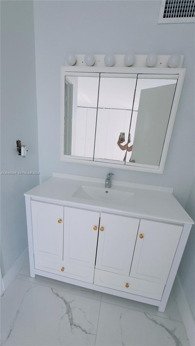 A white bathroom vanity with a mirror and light fixture sits against a light wall — 19851 SW 114th Ave # 301, Miami FL 33157, MIAMI, FL