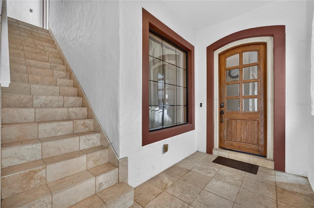 A tiled entryway features a wooden front door, a large window, and stone stairs — 865 DESERT MOUNTAIN COURT, REUNION, FL