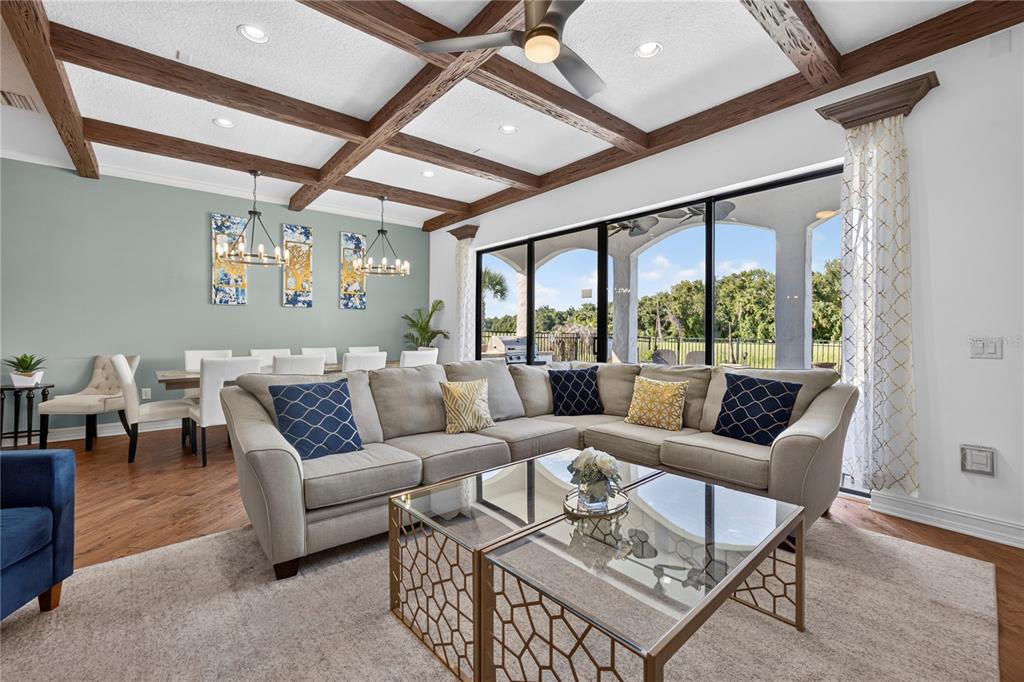 A living room with a coffered ceiling, large sliding glass doors, and an adjacent dining area — 865 DESERT MOUNTAIN COURT, REUNION, FL