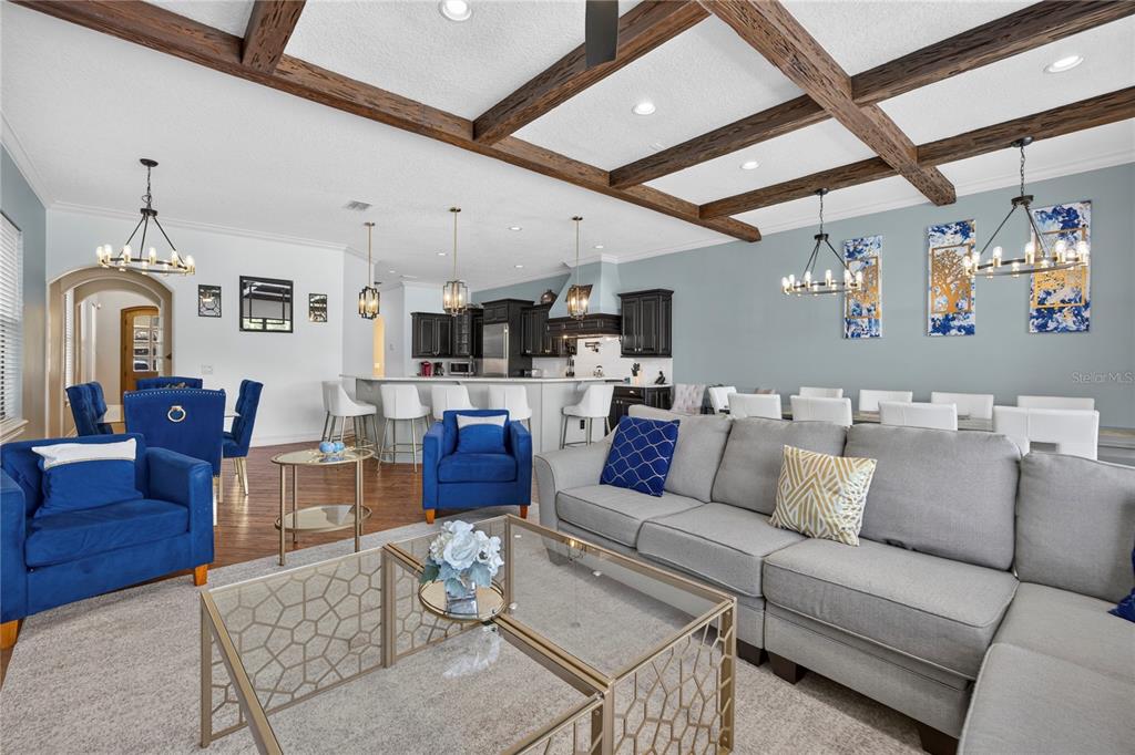An open-concept living and dining area features a coffered ceiling with exposed wooden beams — 865 DESERT MOUNTAIN COURT, REUNION, FL