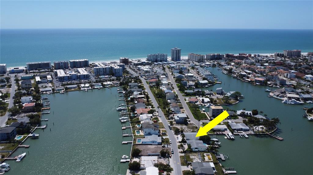 An aerial view shows a waterfront house with a boat dock on a canal — 308 173RD AVENUE E, NORTH REDINGTON BEACH, FL