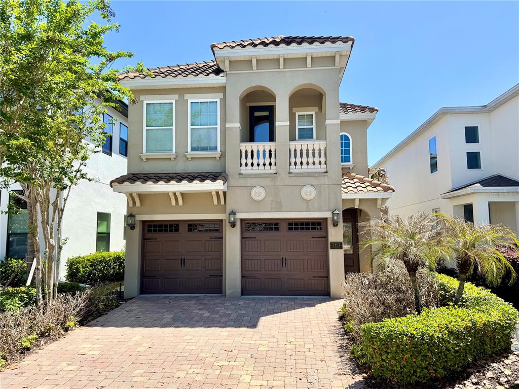 A two-story stucco house features a two-car garage, a balcony, and a paved driveway — 761 DESERT MOUNTAIN COURT, KISSIMMEE, FL