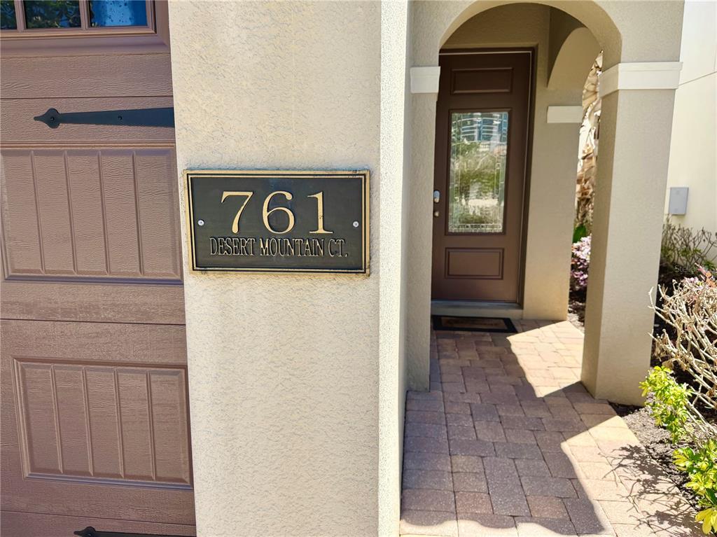 A house number plaque is mounted on the exterior wall next to a garage door — 761 DESERT MOUNTAIN COURT, KISSIMMEE, FL