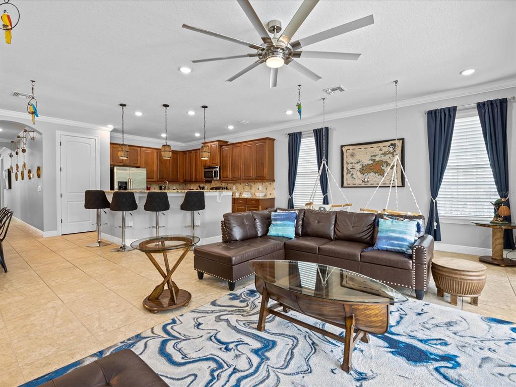 An open-concept living room with a brown sectional sofa, kitchen island, and tile flooring — 761 DESERT MOUNTAIN COURT, KISSIMMEE, FL