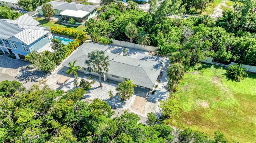 An aerial view shows a single-story house with a gray roof surrounded by lush vegetation — 578 COMPANION WAY, LONGBOAT KEY, FL
