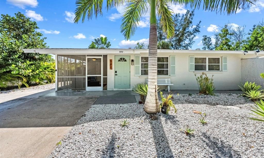 A single-story house with a light green front door, a screened porch, and gravel landscaping — 578 COMPANION WAY, LONGBOAT KEY, FL