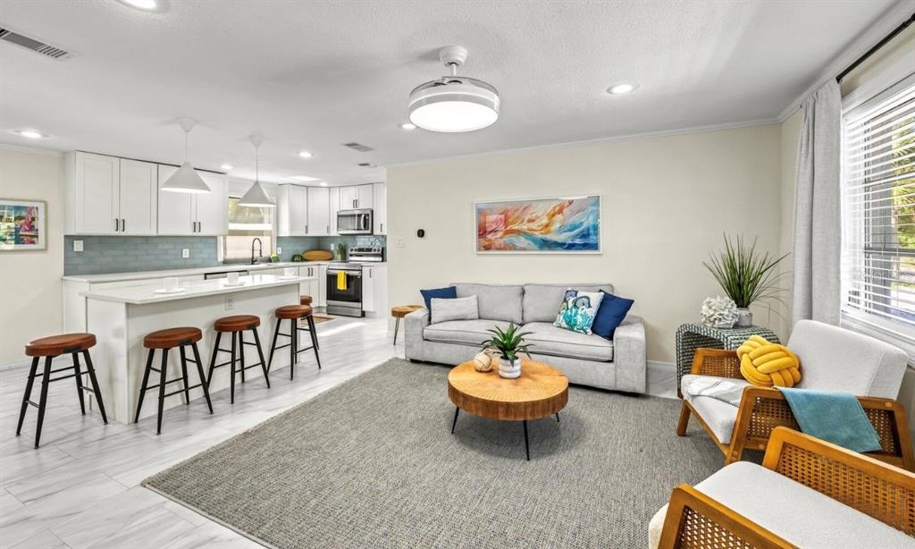An open-concept living room and kitchen featuring white cabinetry, a kitchen island, and gray flooring — 578 COMPANION WAY, LONGBOAT KEY, FL