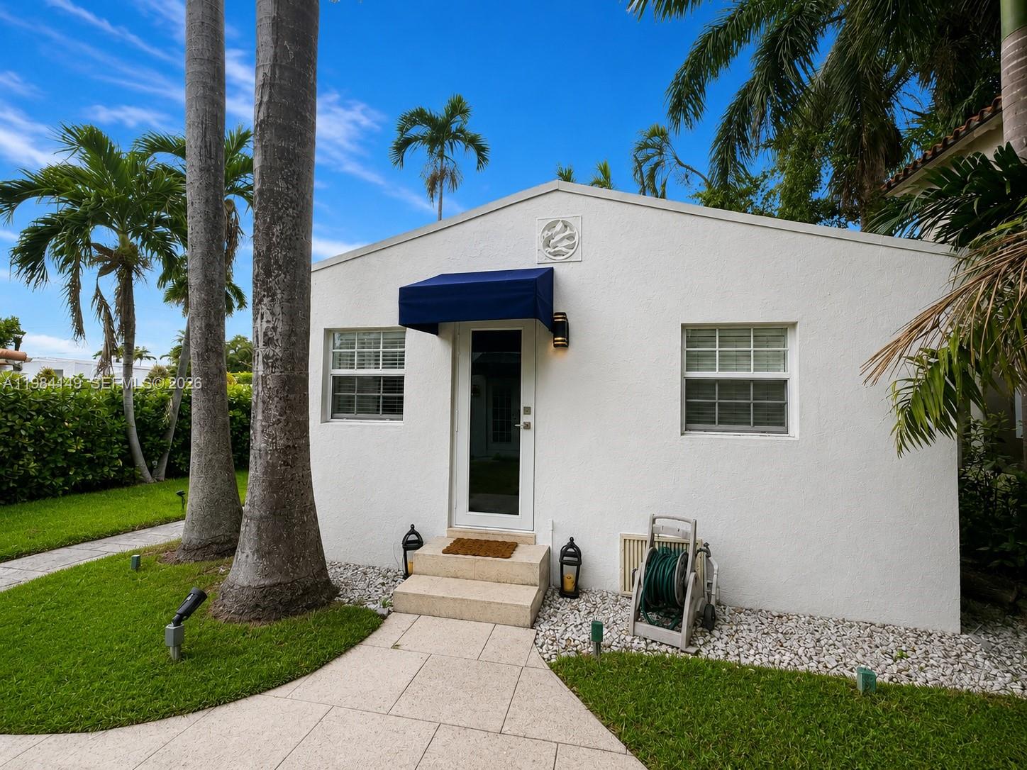 A white, single-story building with a blue awning over the front door and palm trees — 265-B Palm Ave, Miami Beach FL 33139, MIAMI BEACH, FL