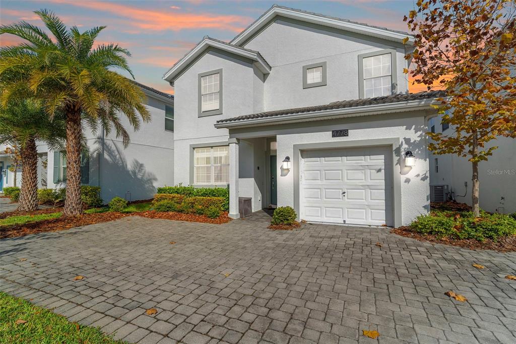 A two-story house with a white stucco exterior, a single-car garage, and a paver driveway — 4778 KINGS CASTLE CIRCLE, KISSIMMEE, FL