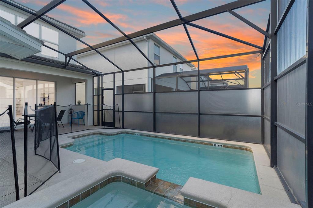 A swimming pool and spa are enclosed within a screened lanai behind a two-story house — 4778 KINGS CASTLE CIRCLE, KISSIMMEE, FL