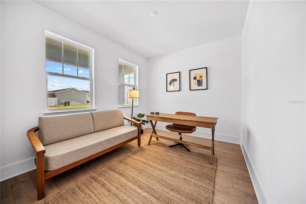 A home office features a sofa, a wooden desk with a chair, and two windows — 1694 PINECLIFF DRIVE, APOPKA, FL