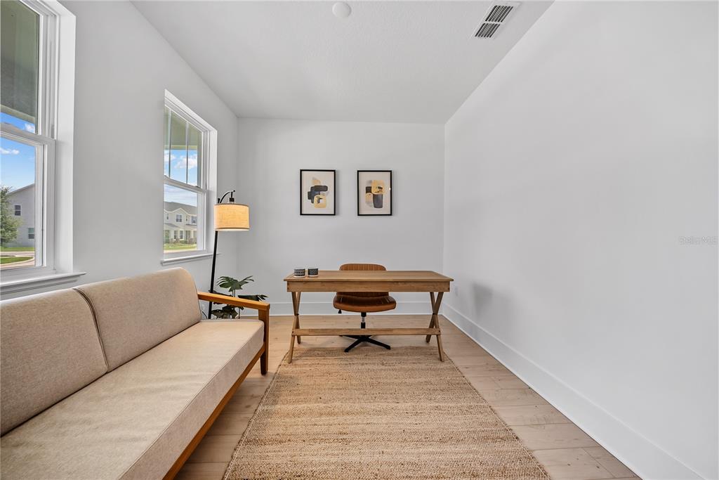 A home office features a wooden desk, a sofa, a rug, and two framed wall prints — 1694 PINECLIFF DRIVE, APOPKA, FL
