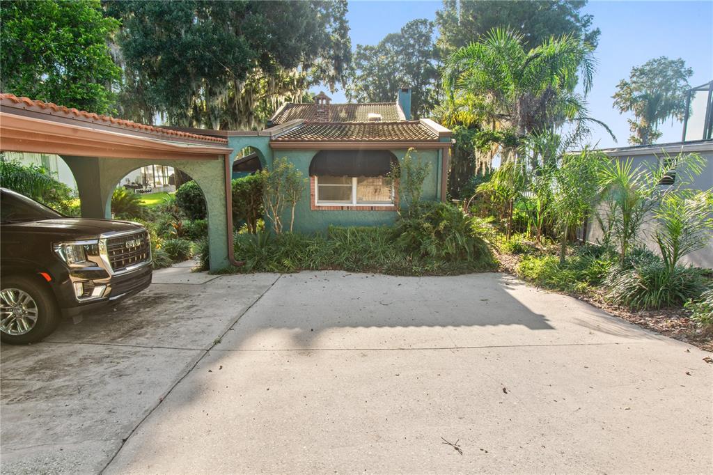 A teal house with a tiled roof and a carport sits behind a concrete driveway — 1019 W LAKE ELOISE TERRACE, WINTER HAVEN, FL