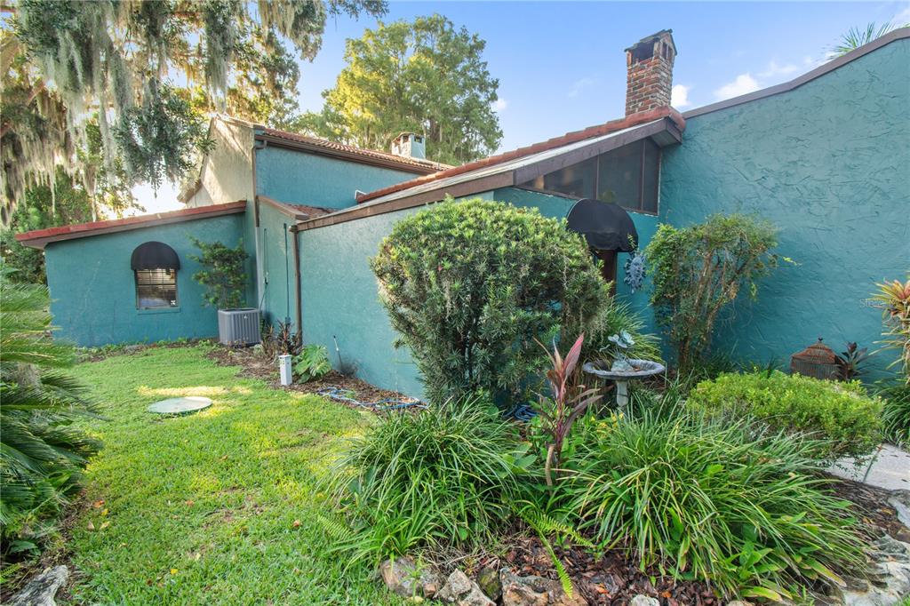 A teal-colored house with a brick chimney and a landscaped yard with a birdbath — 1019 W LAKE ELOISE TERRACE, WINTER HAVEN, FL