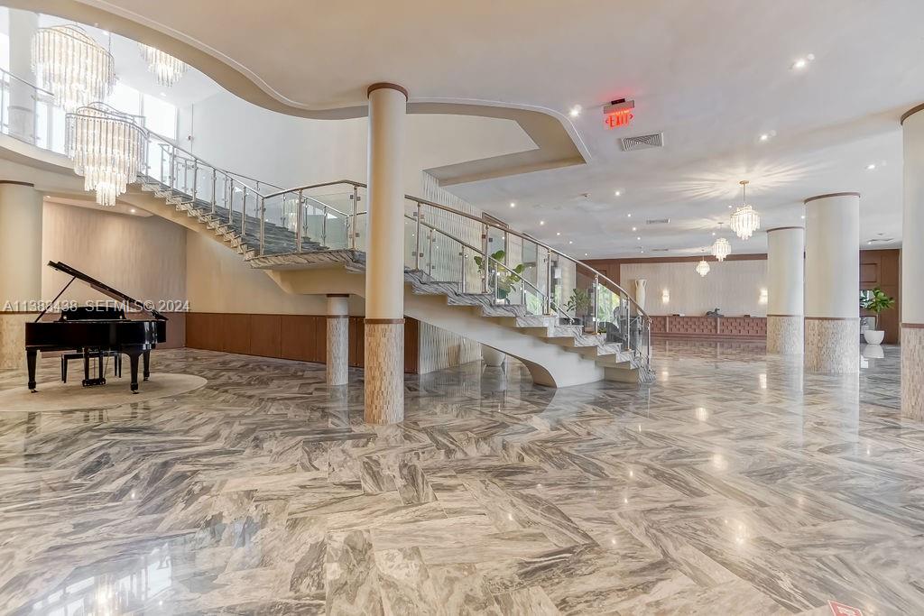 A grand lobby features a sweeping staircase, marble floors, crystal chandeliers, and a grand piano — 5401 Collins Ave # 601, Miami Beach FL 33140, MIAMI BEACH, FL