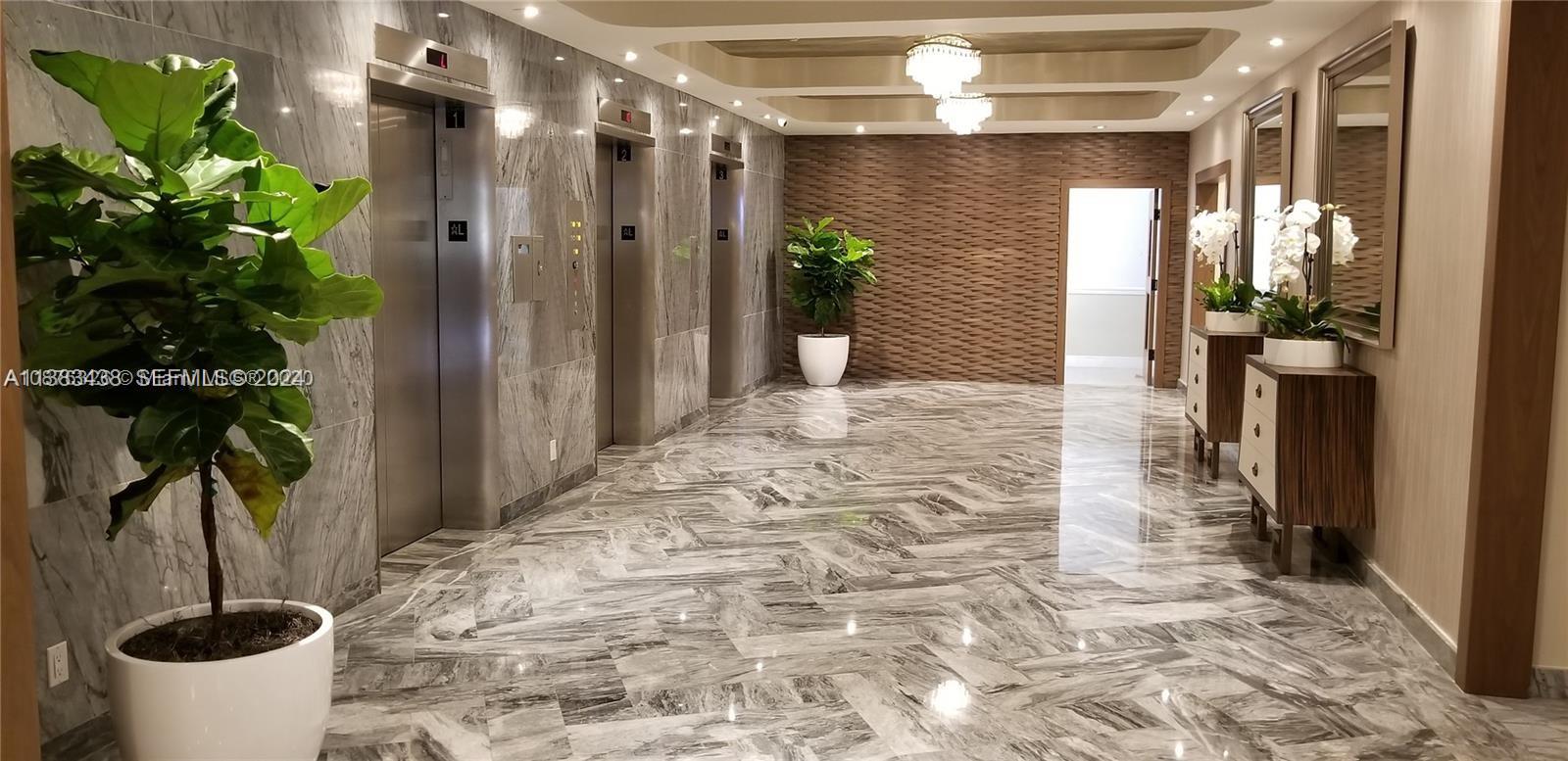 A modern elevator lobby features gray marble floors, stainless steel doors, and textured wall accents — 5401 Collins Ave # 601, Miami Beach FL 33140, MIAMI BEACH, FL