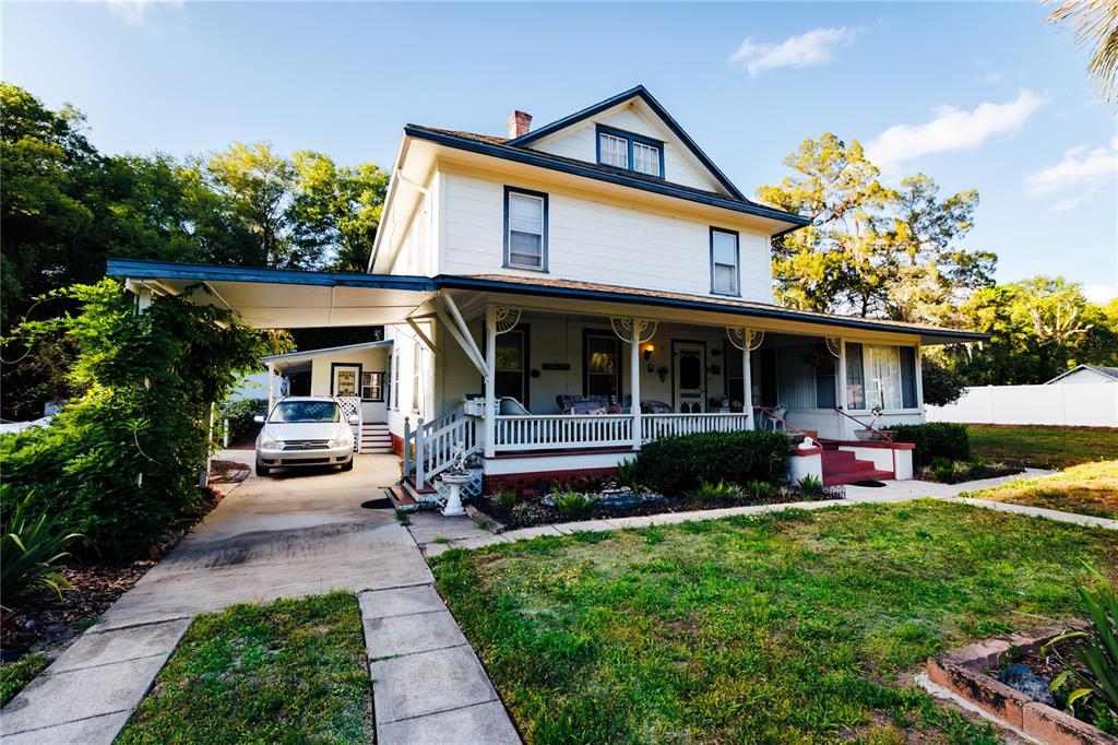 A two-story white house with a wrap-around porch and a carport over the driveway — 215 E FRENCH AVENUE, ORANGE CITY, FL
