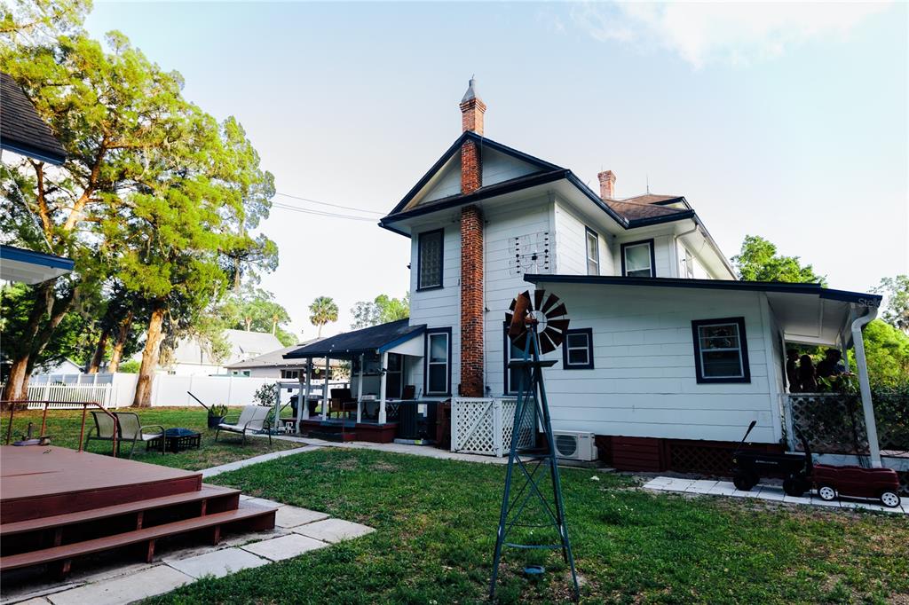 A two-story white house with a brick chimney and a decorative windmill in the yard — 215 E FRENCH AVENUE, ORANGE CITY, FL