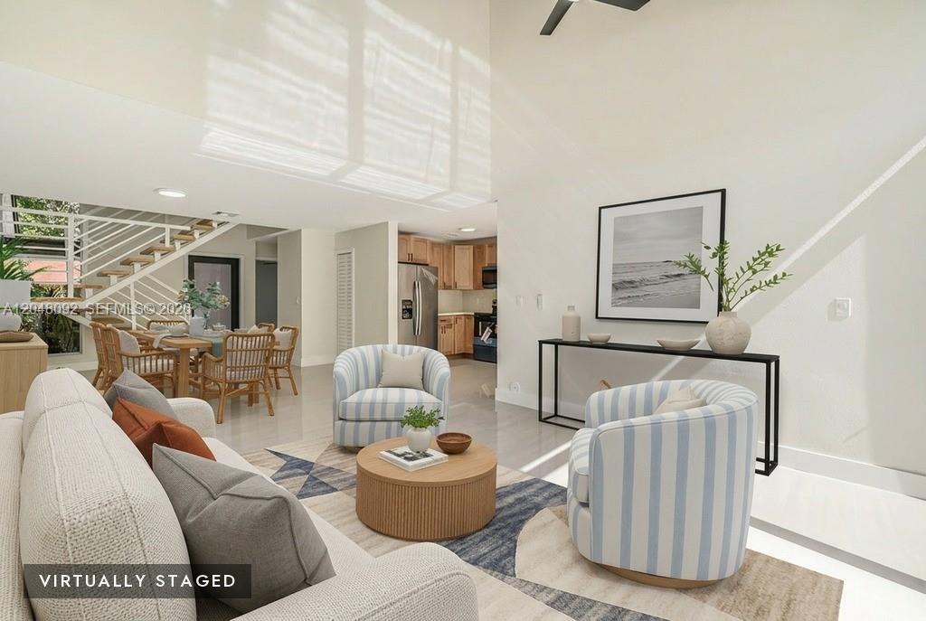 This virtually staged living room features a high ceiling, striped armchairs, and an open kitchen — 11621 SW 90th St, Miami FL 33176, MIAMI, FL