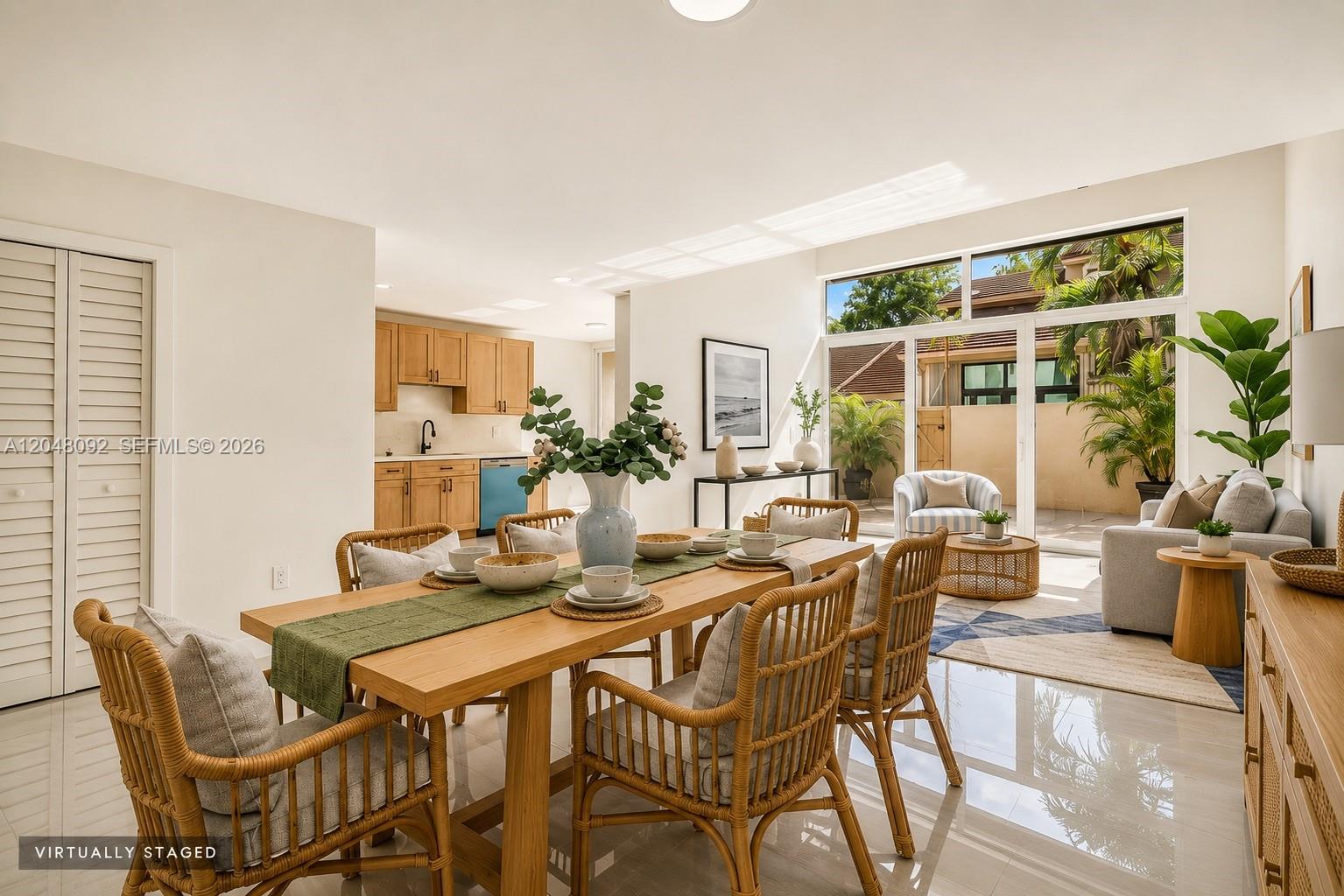 A dining area with a wooden table and rattan chairs opens into a bright living room — 11621 SW 90th St, Miami FL 33176, MIAMI, FL