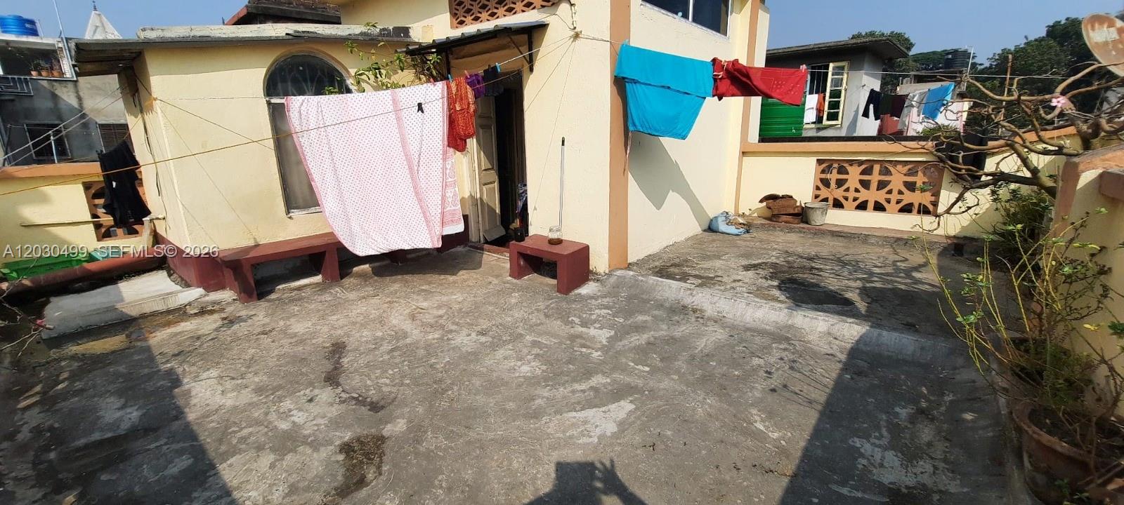 A concrete rooftop terrace features laundry hanging on lines and a small building entrance — 2/1 Rajani Mukherjee Road, Kolkata, India, 700038, FL