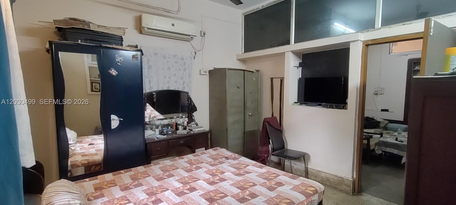 A bedroom features a bed, a dark blue wardrobe with a mirror, and a television — 2/1 Rajani Mukherjee Road, Kolkata, India, 700038, FL