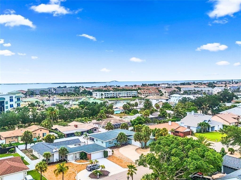 An aerial view of a residential neighborhood with houses, trees, and a distant bay — 409 4TH AVENUE N, TIERRA VERDE, FL