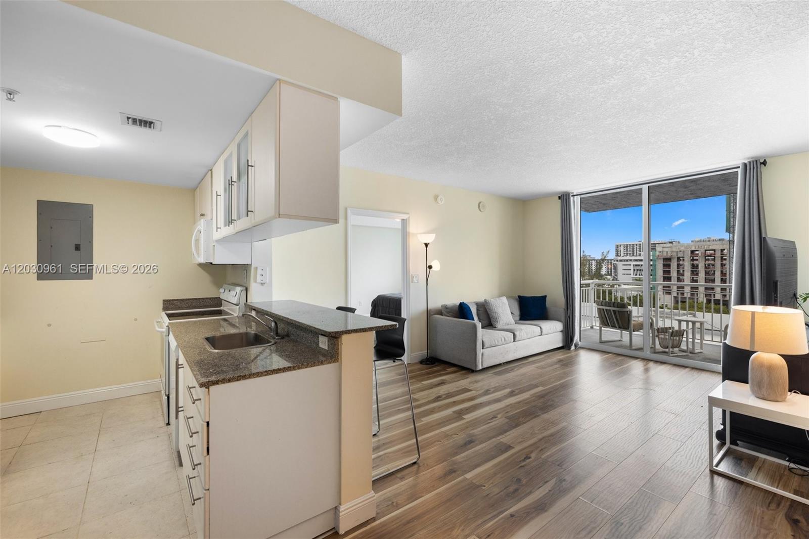 An open-concept kitchen and living area with wood-look flooring and a balcony with city views — 275 NE 18th St # 710, Miami FL 33132, MIAMI, FL
