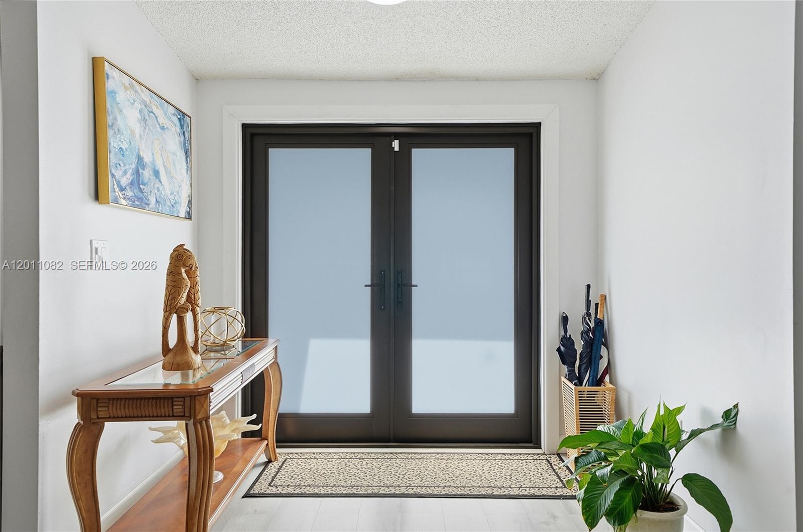 An entryway features a wooden console table, double glass doors, and a potted plant — 20102 NW 62nd Ave, Miami FL 33015, MIAMI, FL