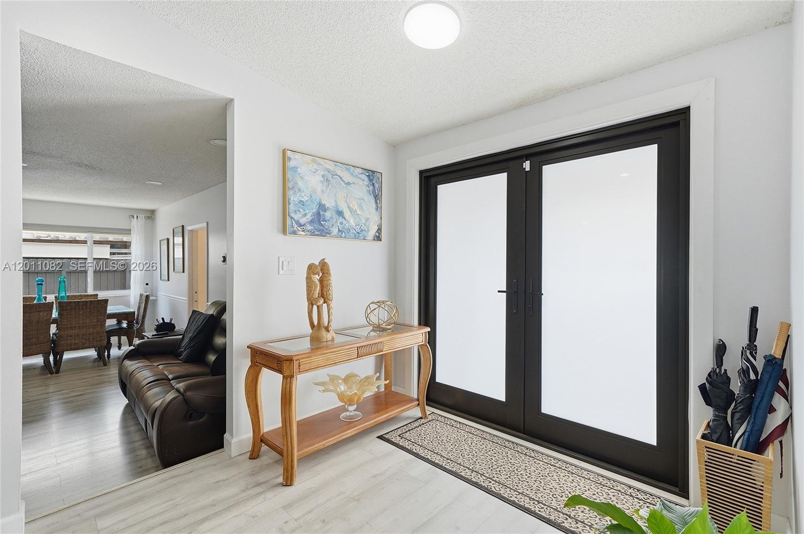An entryway features a wooden console table, a patterned rug, and double glass doors — 20102 NW 62nd Ave, Miami FL 33015, MIAMI, FL