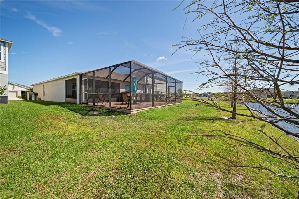A house with a screened-in patio overlooking a grassy yard and a pond — 5543 ARLINGTON RIVER DRIVE, LAKELAND, FL