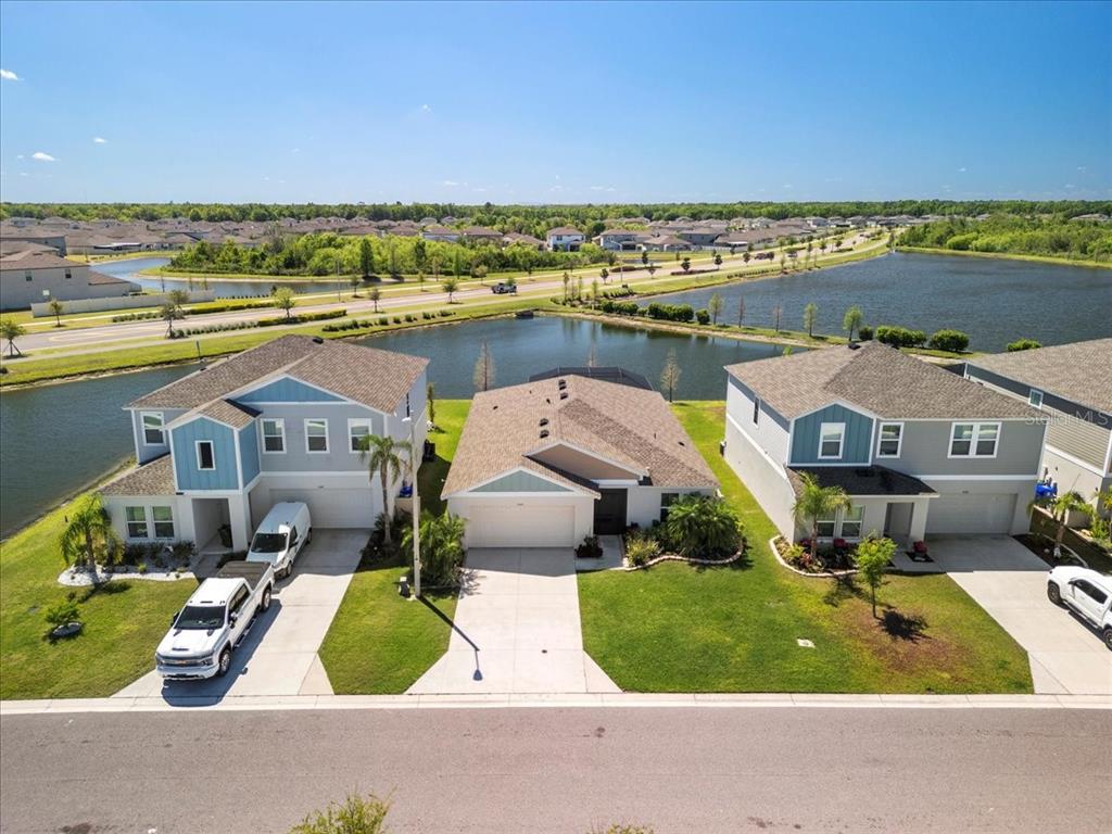 An aerial view shows three suburban houses situated along a pond in a residential neighborhood — 5543 ARLINGTON RIVER DRIVE, LAKELAND, FL
