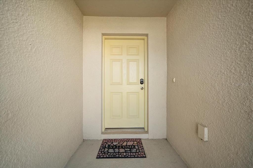 A light-colored front door with a welcome mat sits in a recessed entryway — 5543 ARLINGTON RIVER DRIVE, LAKELAND, FL