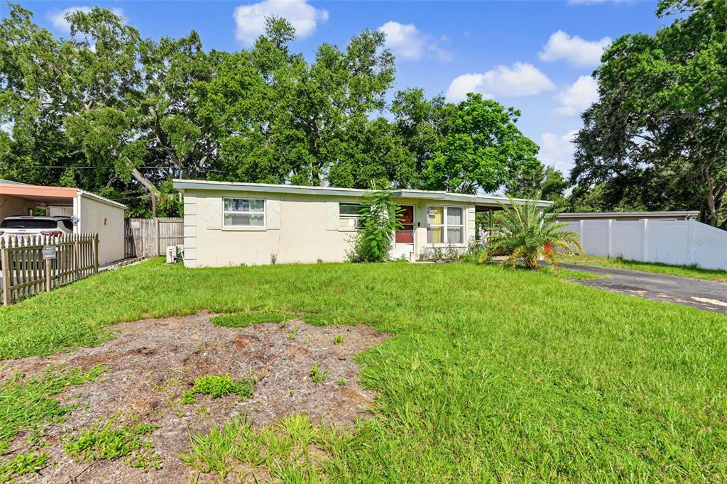 A single-story house with a light-colored exterior, a front lawn, and a white fence — 9374 84TH STREET, SEMINOLE, FL