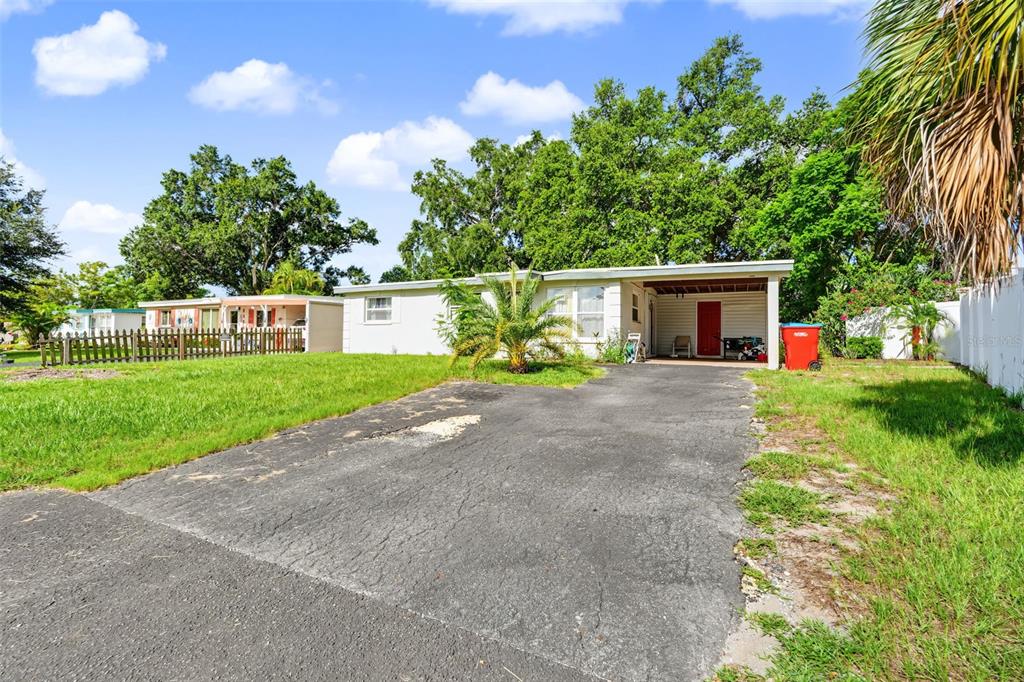 A single-story house with a white exterior, a red front door, and a paved driveway — 9374 84TH STREET, SEMINOLE, FL