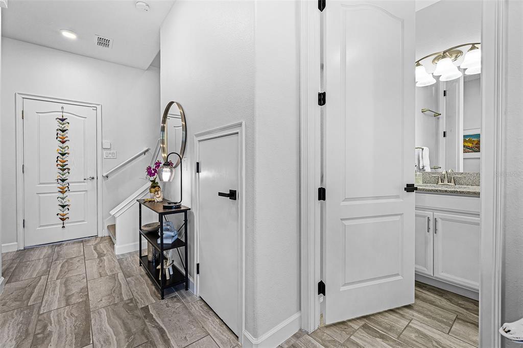 A tiled entryway features a front door, a small storage closet, and a half bathroom — 1317 SHINNECOCK HILLS DRIVE, DAVENPORT, FL