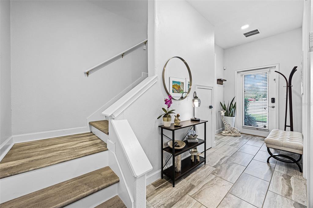 An entryway features a staircase with wood-look steps, a console table, and a front door — 1317 SHINNECOCK HILLS DRIVE, DAVENPORT, FL