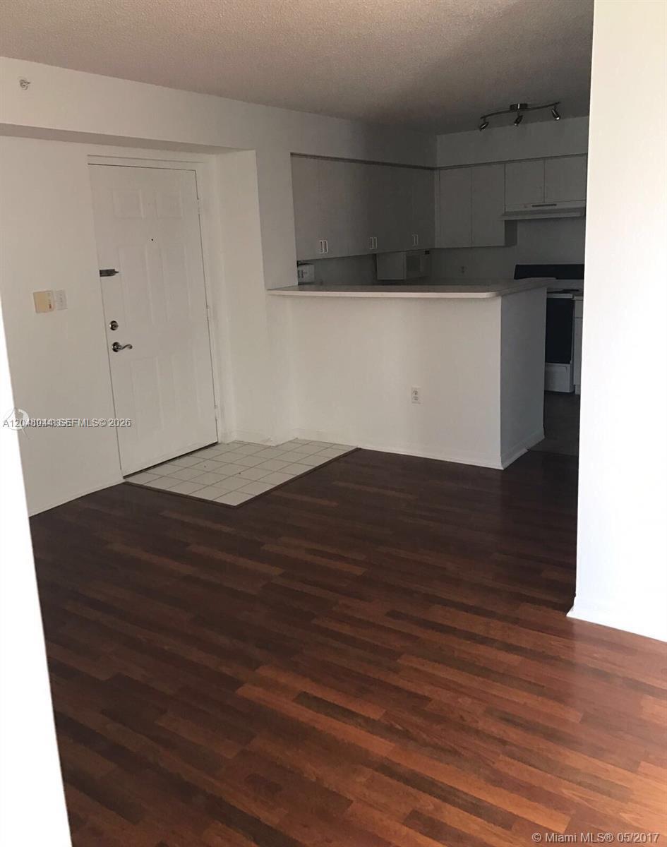An interior view shows a kitchen with white cabinets and a breakfast bar near an entrance — 4420 NW 107th Ave # 207, Doral FL 33178, DORAL, FL