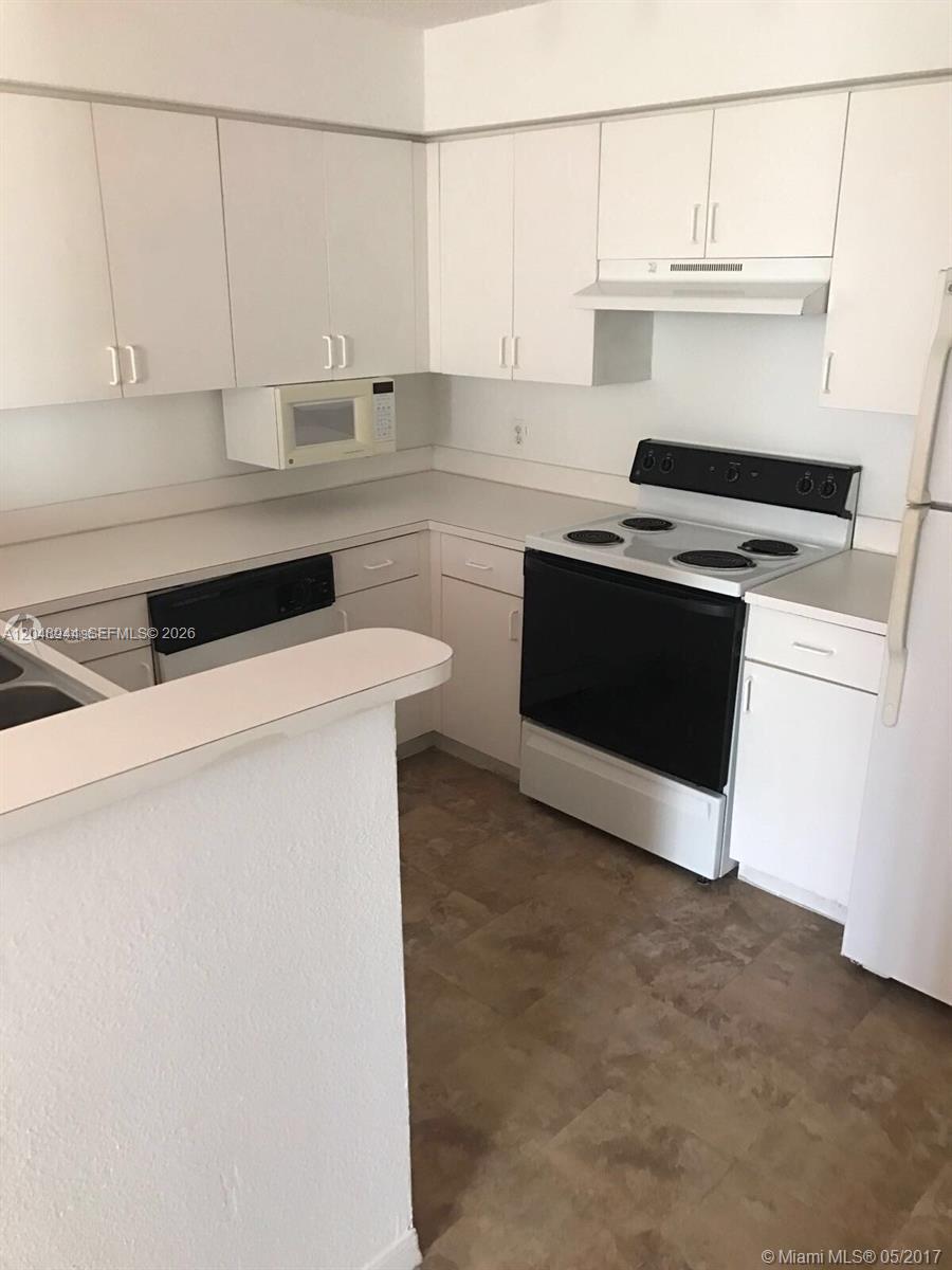 A kitchen features white cabinets, white countertops, a black stove, and a black dishwasher — 4420 NW 107th Ave # 207, Doral FL 33178, DORAL, FL