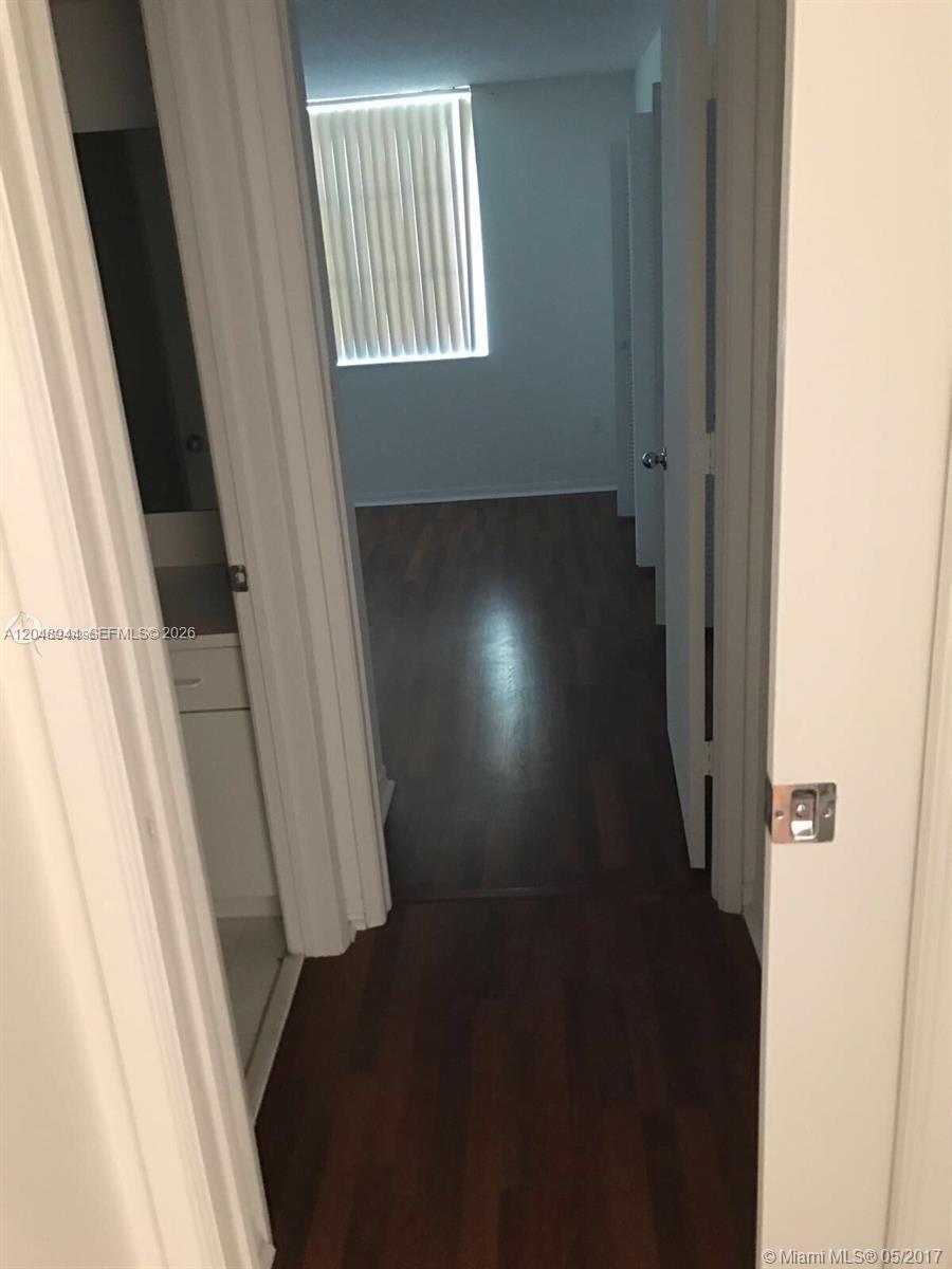A hallway with dark wood flooring leads into a bedroom with a window — 4420 NW 107th Ave # 207, Doral FL 33178, DORAL, FL