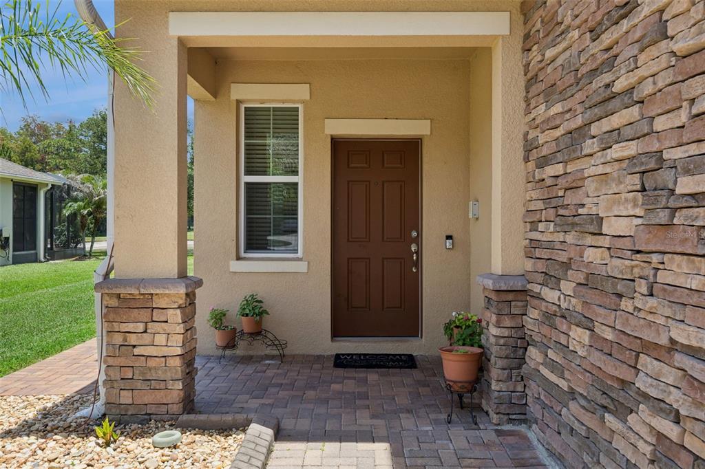 A covered entryway features a brown front door, stone accents, and a brick paver porch — 10555 ARBOR VIEW BOULEVARD, ORLANDO, FL