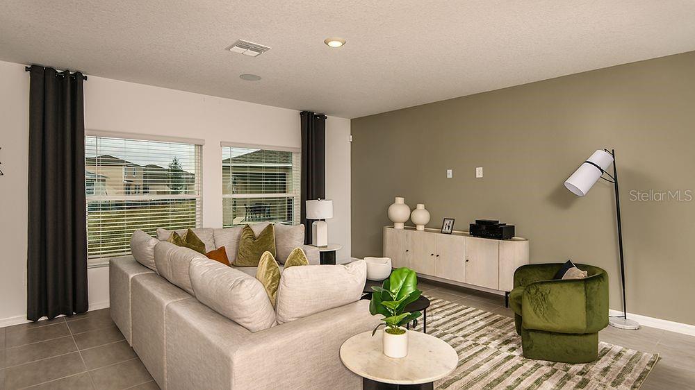 A living room features a large sectional sofa, a console table, and a green armchair — 140 BRINSMEAD ROAD, HAINES CITY, FL