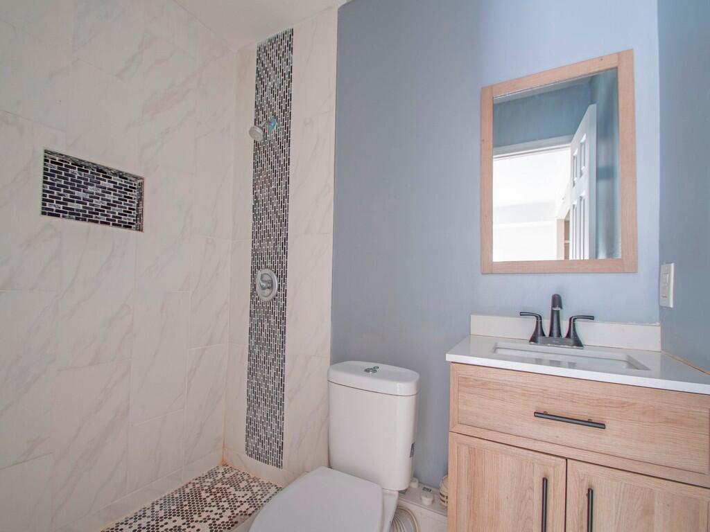 A bathroom features a walk-in shower with marble-look tile, a vanity, and a toilet — 1846 24th Place SW, Vero Beach FL 32962, VERO BEACH, FL