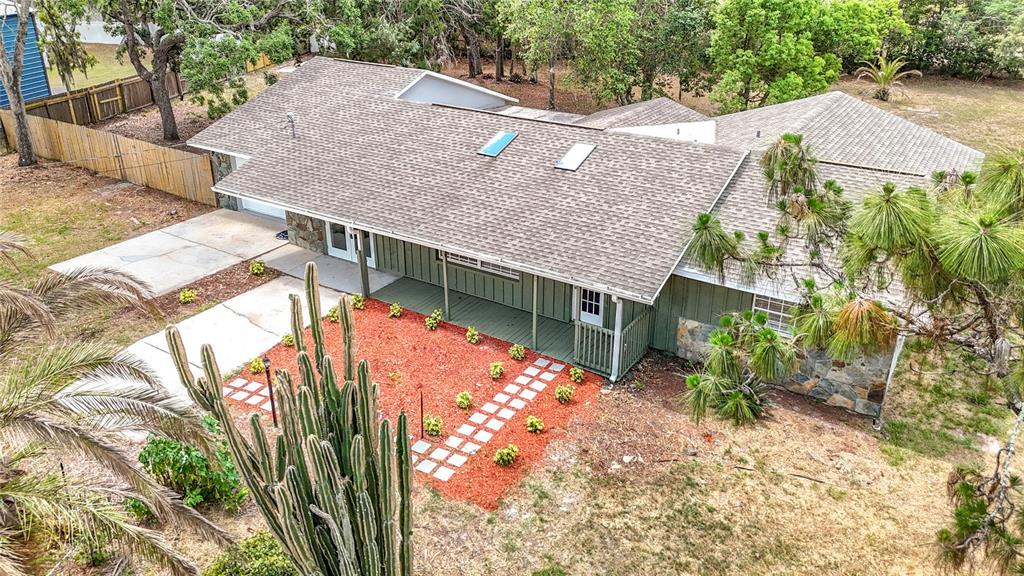 An aerial view of a single-story house with a shingled roof, skylights, and stone accents — 13206 TYRONE STREET, HUDSON, FL