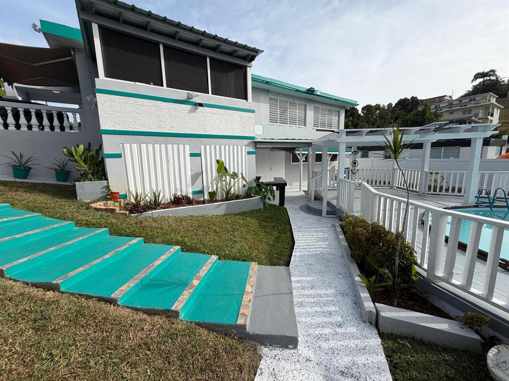 A house exterior features teal-painted stairs, a white fence, and a swimming pool area — 282 AVE. FELIX RIOS, AIBONITO, PR
