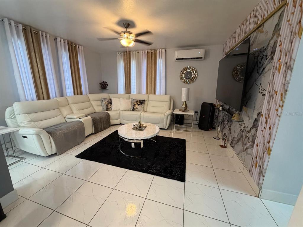 A living room features a white sectional sofa, a round coffee table, and a large television — 282 AVE. FELIX RIOS, AIBONITO, PR