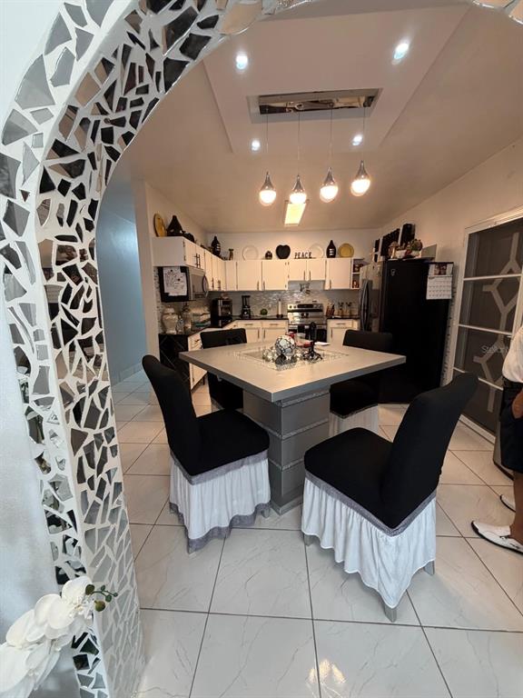 A dining area features a square table with black-and-white chairs under a modern light fixture — 282 AVE. FELIX RIOS, AIBONITO, PR