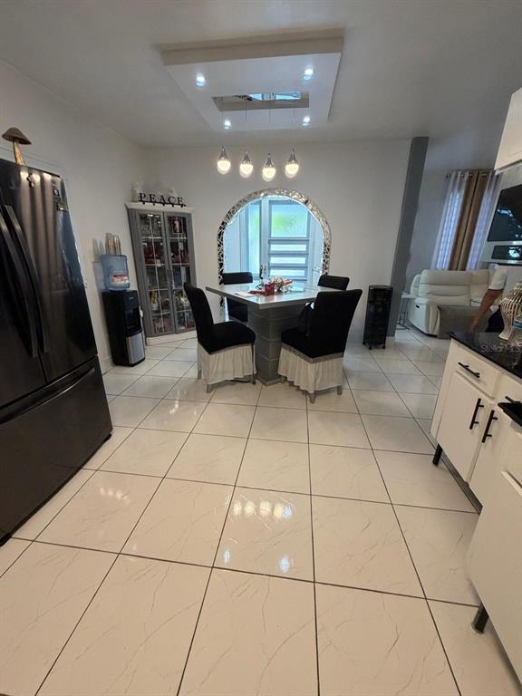 A kitchen and dining area with white tiled floors, a square table, and black chairs — 282 AVE. FELIX RIOS, AIBONITO, PR